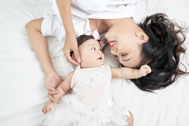 Young mother and cute baby on bed at home - Foto, Imagen
