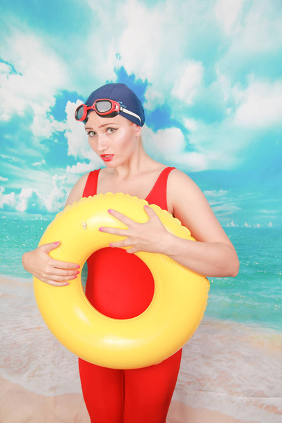 Studio shot of Beauty sexy women wear red vintage swimsuit and carrying life ring on blue sky background - Photo, Image
