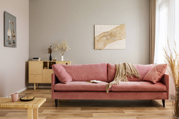 Comfortable velvet pastel pink couch in elegant beige interior with abstract painting - Fotó, kép