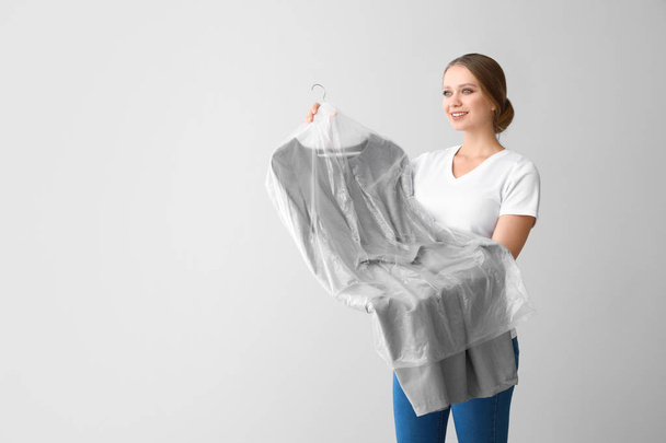 Γυναίκα με ρούχα μετά από Στεγνό καθάρισμα σε ανοιχτόχρωμο φόντο - Φωτογραφία, εικόνα