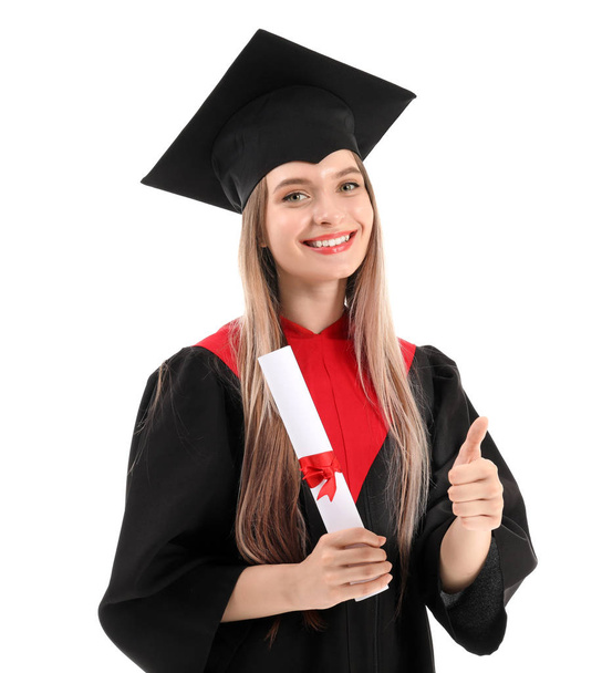 Young female student in bachelor robe showing thumb-up on white background - Fotografie, Obrázek