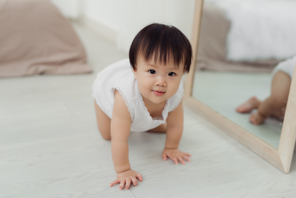Adorable little baby girl crawling on floor in room - Photo, Image