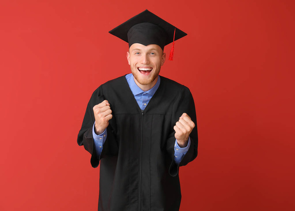 Szczęśliwy męski student w Kawalerskim szacie na kolorowym tle - Zdjęcie, obraz
