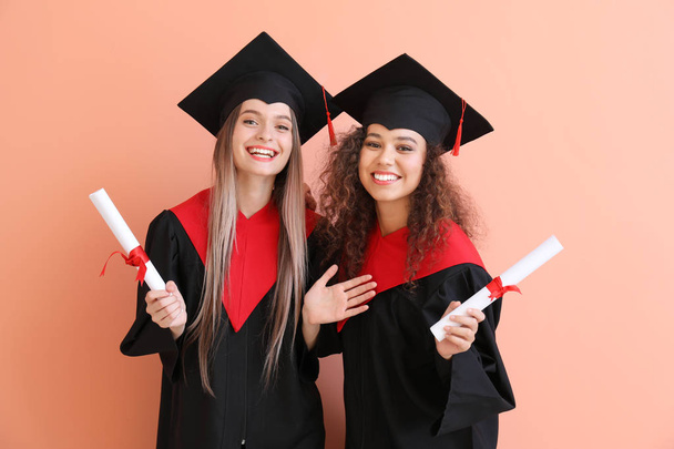 Young students in bachelor robes on color background - Photo, image
