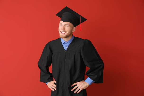 Young male student in bachelor robe on color background - Photo, Image