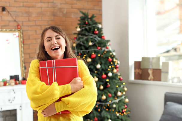 Happy young woman with Christmas gift at home - Foto, Imagem