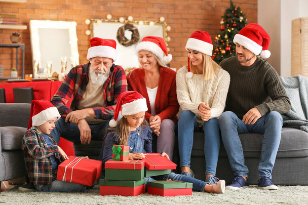 Pienet lapset perheensä kanssa avaavat joululahjoja kotona
 - Valokuva, kuva