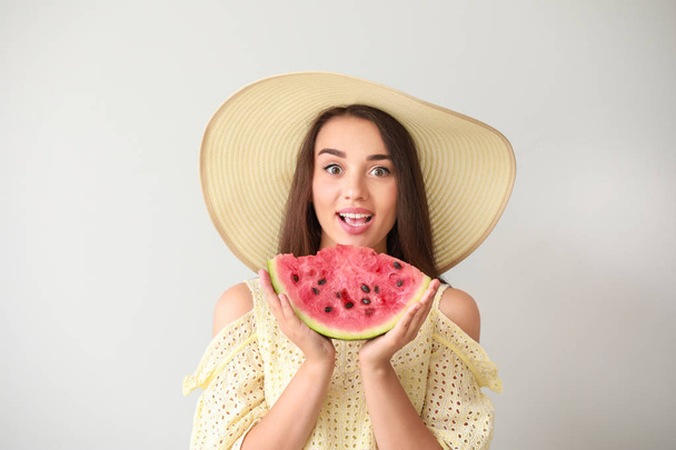 Beautiful young woman with slice of fresh watermelon on light background - Photo, Image