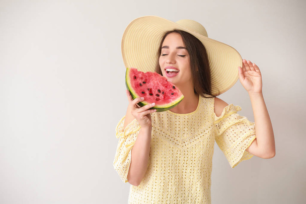 Beautiful young woman with slice of fresh watermelon on light background - Photo, Image