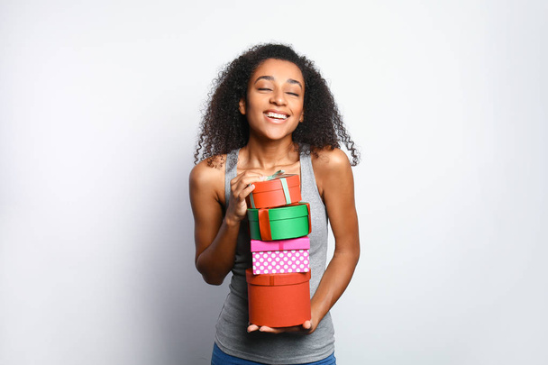 Portrait of beautiful African-American woman with gift boxes on white background - Φωτογραφία, εικόνα
