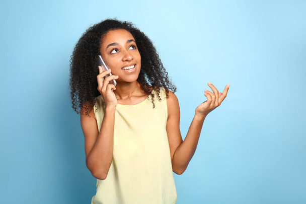 Портрет красивой афро-американской женщины, разговаривающей по мобильному телефону на цветном фоне
 - Фото, изображение