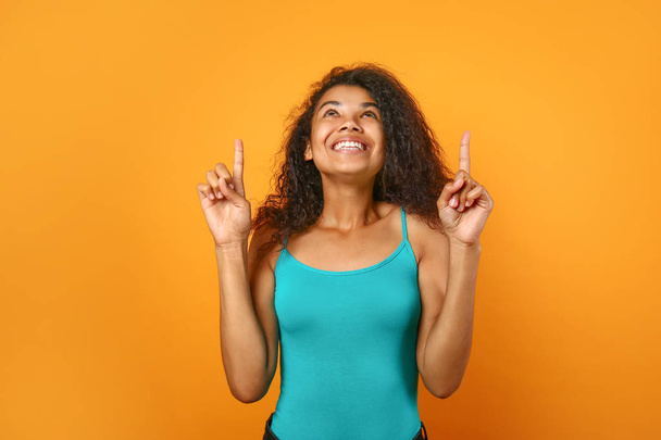 Щасливий молодий афро-американської жінки вказуючи на щось на колір фону - Фото, зображення