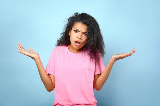Displeased young African-American woman on color background - Photo, Image