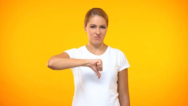 Dissatisfied female showing thumbs down, negative feedback, wrong choice dislike - Foto, afbeelding