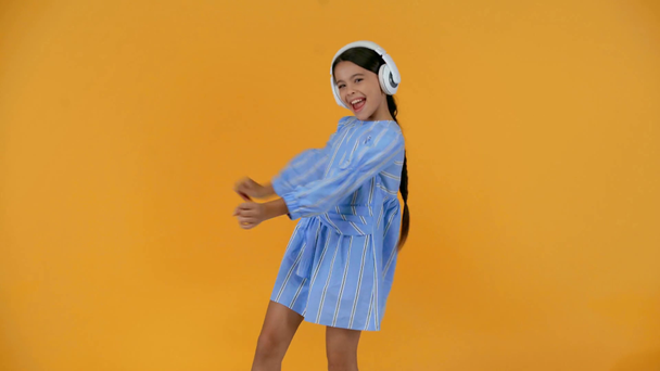 boldog preteen gyermek kék ruhát hallgat zenét fejhallgató - Felvétel, videó