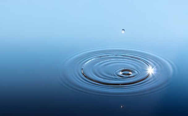 Drop isolated in blue water with sunbeam - Photo, Image
