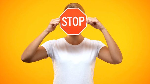 Young woman holding red stop sign front face, negative reaction, warning problem - 写真・画像