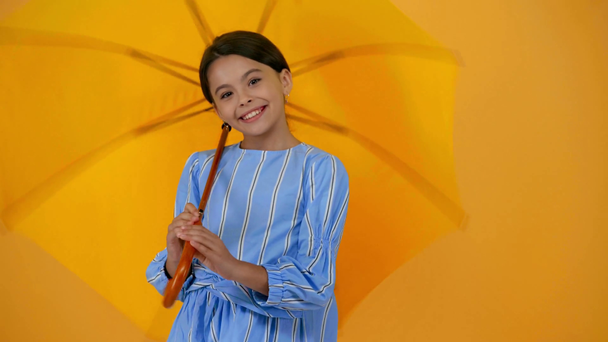 niño preadolescente feliz en vestido azul con paraguas amarillo
 - Metraje, vídeo