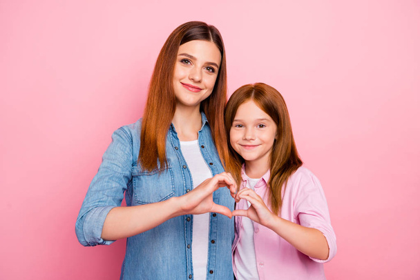Pretty foxy small lady and her mom making heart figure with hands wear casual clothes isolated pink background - Foto, imagen