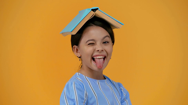 παιδί με βιβλίο στο κεφάλι που δείχνει τη γλώσσα και διαφορετικές χειρονομίες - Πλάνα, βίντεο