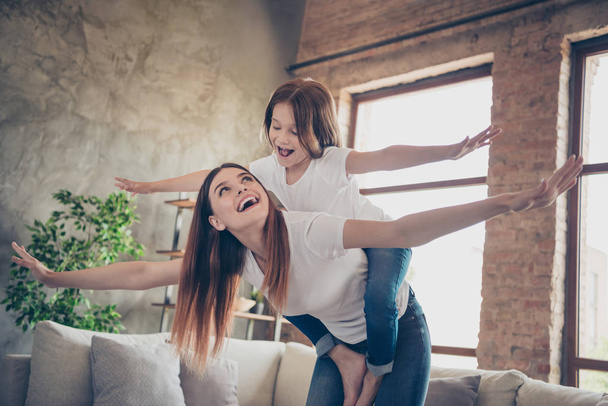 Portrait of cheerful parent kid laughing wearing white t-shirt denim jeans looking standing in house indoors - Fotó, kép