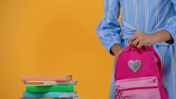 sırt çantasına kitap koyarak kız öğrencinin kırpılmış görünümü - Video, Çekim