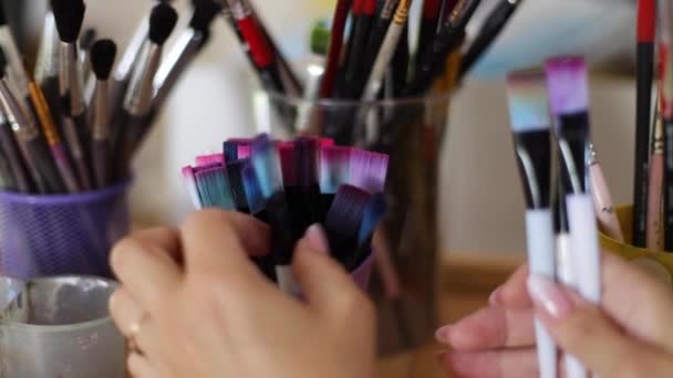 Woman choose brush for painting. Art concept. A lot of brushes in Drawing studio. Close up of hands with brush - Footage, Video