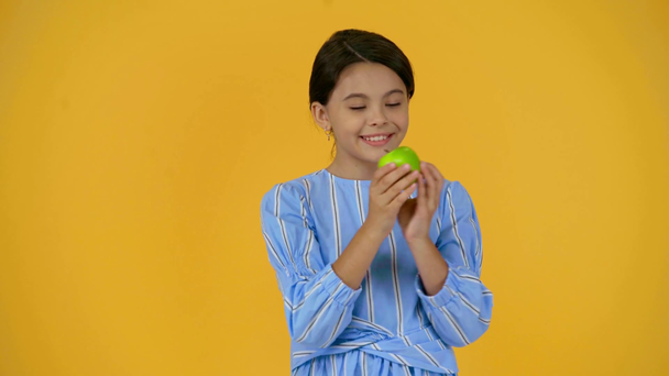 Yeşil elma tutan mutlu çocuk sarı üzerinde izole - Video, Çekim