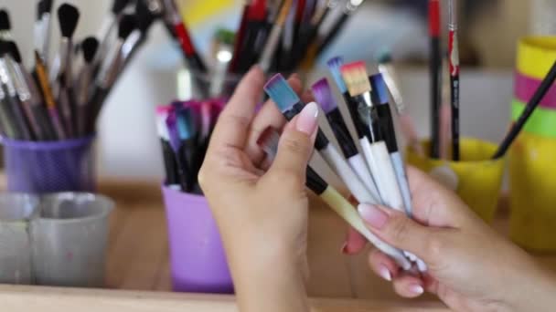 Kadın resim için fırça seçin. Sanat konsepti. Çizim stüdyosunda bir sürü fırça var. Fırça ile ellerinizi kapatın - Video, Çekim