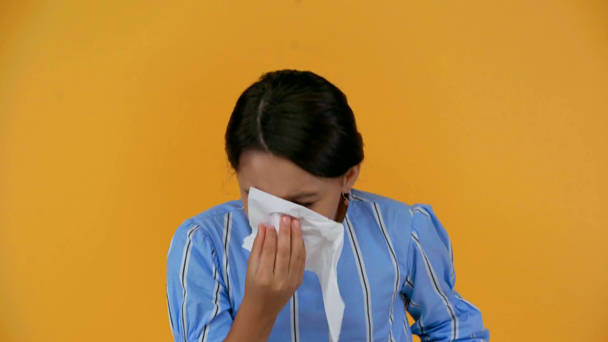 sick child sneezing and blowing her nose in napkin isolated on yellow - Felvétel, videó