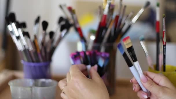 Kadın resim için fırça seçin. Sanat konsepti. Çizim stüdyosunda bir sürü fırça var. Fırça ile ellerinizi kapatın - Video, Çekim