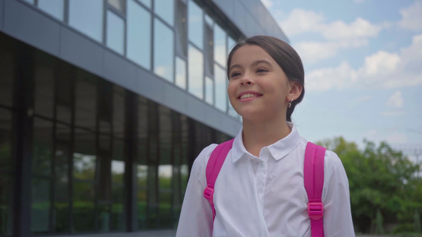 Lächelnde Schülerin mit Rucksack läuft auf Schulhof - Filmmaterial, Video