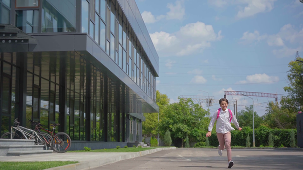 Gelukkig schoolmeisje met rugzak running in schoolplein - Video