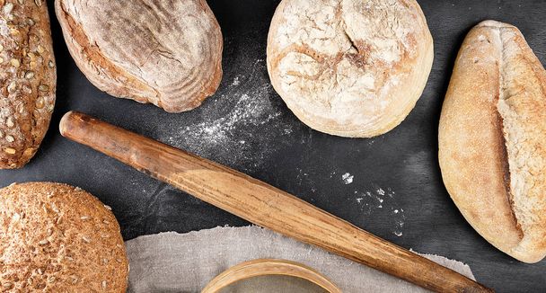 baked various loaves of bread and old rolling pin  - Foto, Imagen