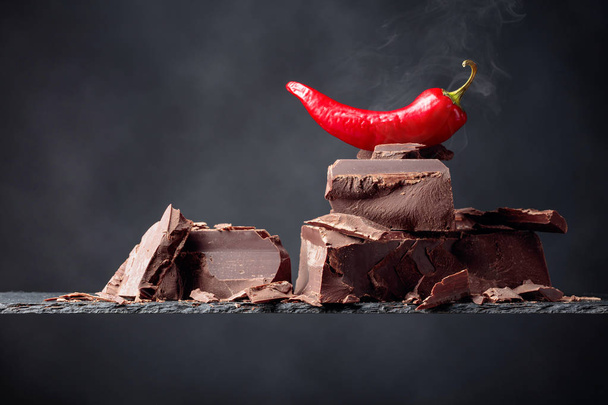 Black chocolate with red pepper on a dark background.  - Photo, Image