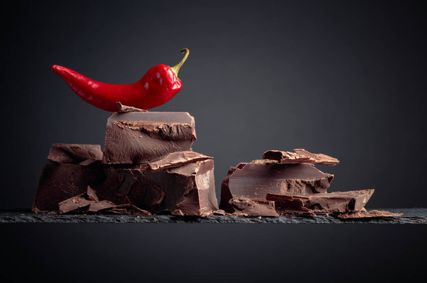 Schwarze Schokolade mit rotem Pfeffer auf dunklem Hintergrund.  - Foto, Bild