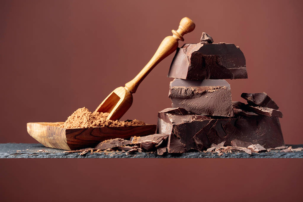 Black chocolate and wooden dish with cocoa powder on a brown bac - Photo, Image