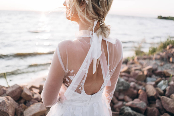 back view of stylish bride standing on the beach at the sunset  - Fotografie, Obrázek