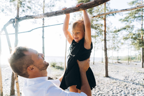 father helping her daughter hanging on the tree  in the forest  - Foto, Bild