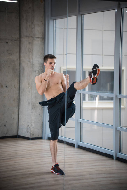 Un homme athlétique debout dans la pose de combat dans le studio montrant le coup de pied
 - Photo, image