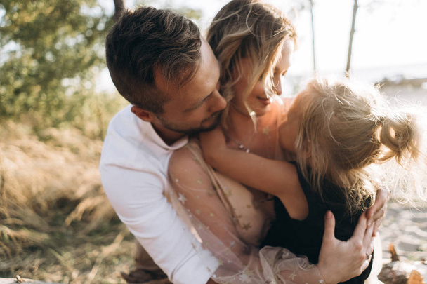 Portrait of family of three hugging together outdoors - Foto, imagen
