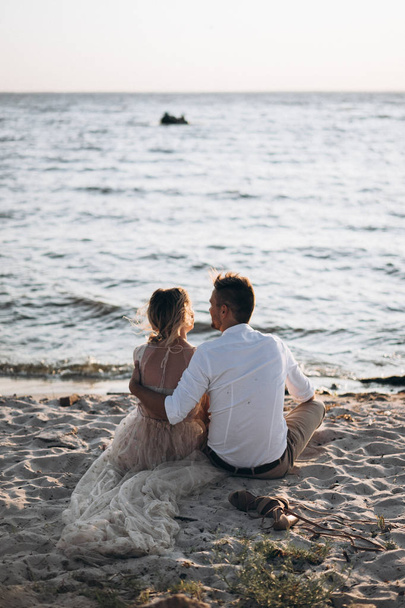 back view of couple sitting on the beach at the sunset  - Valokuva, kuva