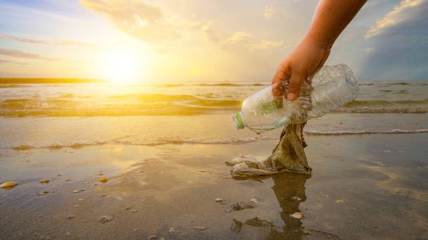 Το χέρι μαζεύει σκουπίδια στην παραλία, η ιδέα της διατήρησης του περιβάλλοντος - Φωτογραφία, εικόνα
