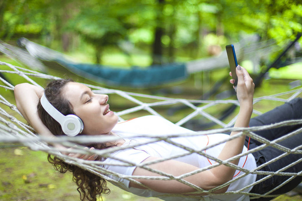 Young woman on hammock listening music - Φωτογραφία, εικόνα