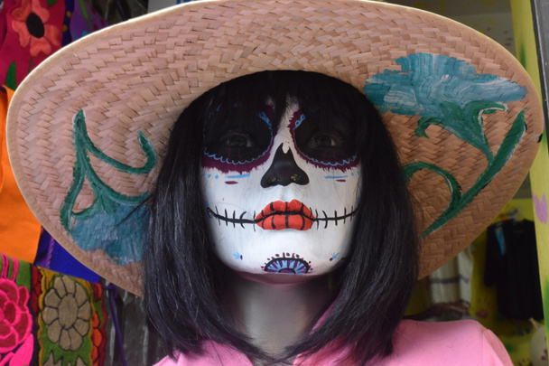 Manken, Meksika 'da Da de Muertos için renkli bir kafatası makyajı ve şapka takıyor. - Fotoğraf, Görsel