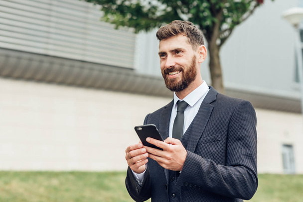 Handsome man in suit using smartphone - Foto, afbeelding