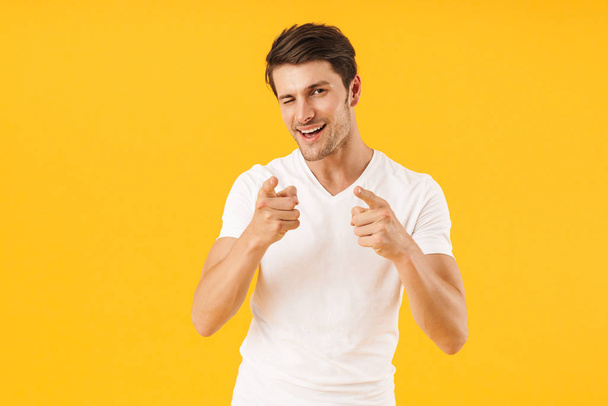 Photo of joyful man in basic t-shirt gesturing index fingers on  - Photo, image