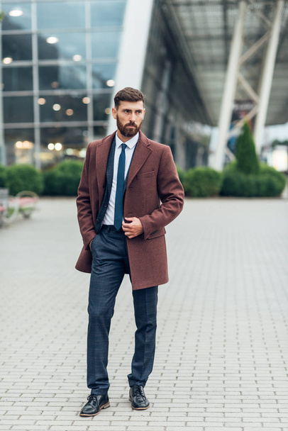 stylischer Typ im Mantel, der draußen posiert - Foto, Bild