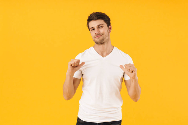 Photo of attractive man in basic t-shirt looking at camera and g - Foto, afbeelding