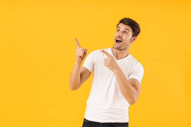 Photo of surprised man in basic t-shirt wondering and gesturing  - Foto, afbeelding
